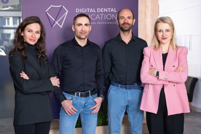 Członkowie zespołu edukacyjnego Digital Dental Education na tle firmowego rollupa